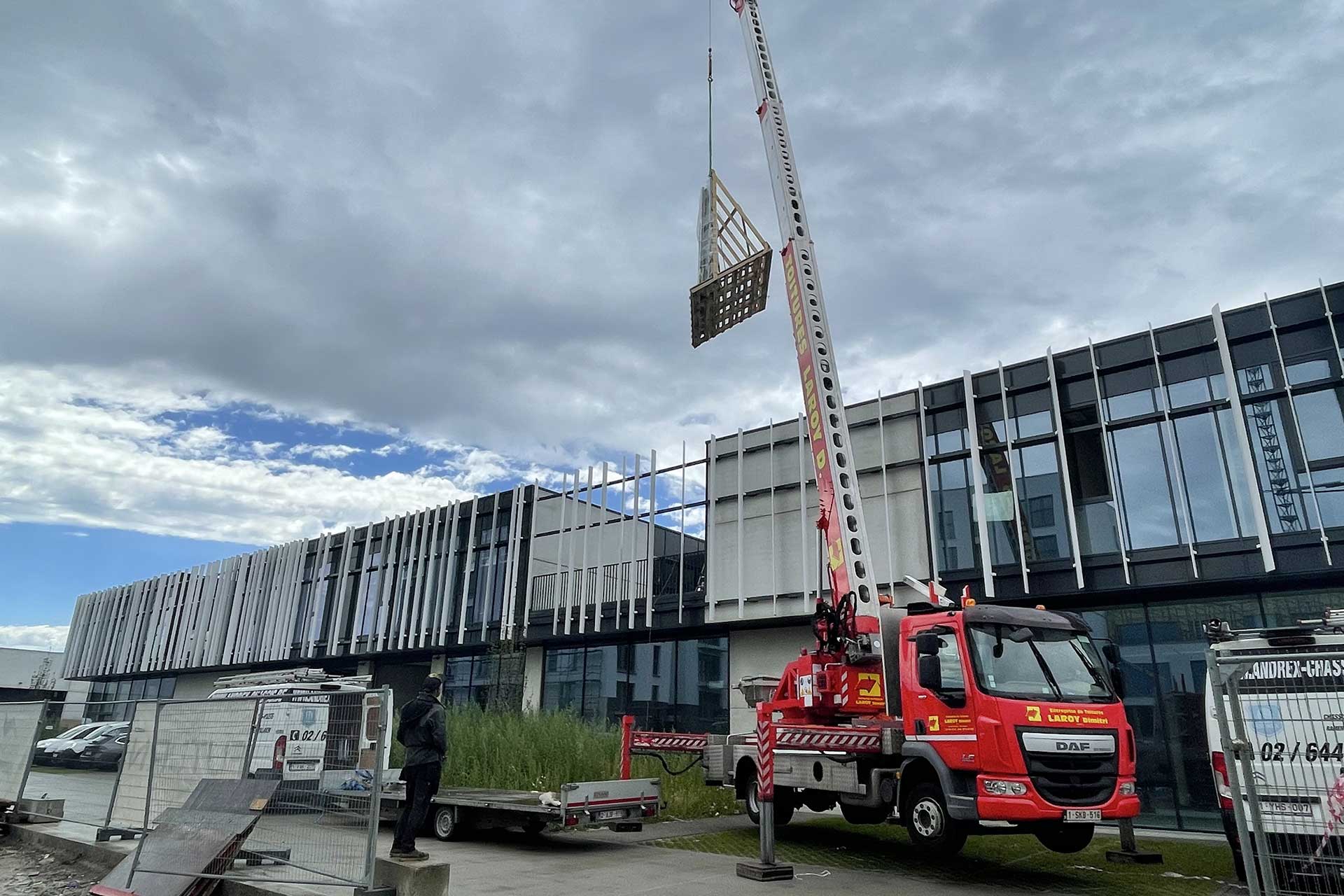 Grue levant un panneau pour la façade d'un immeuble