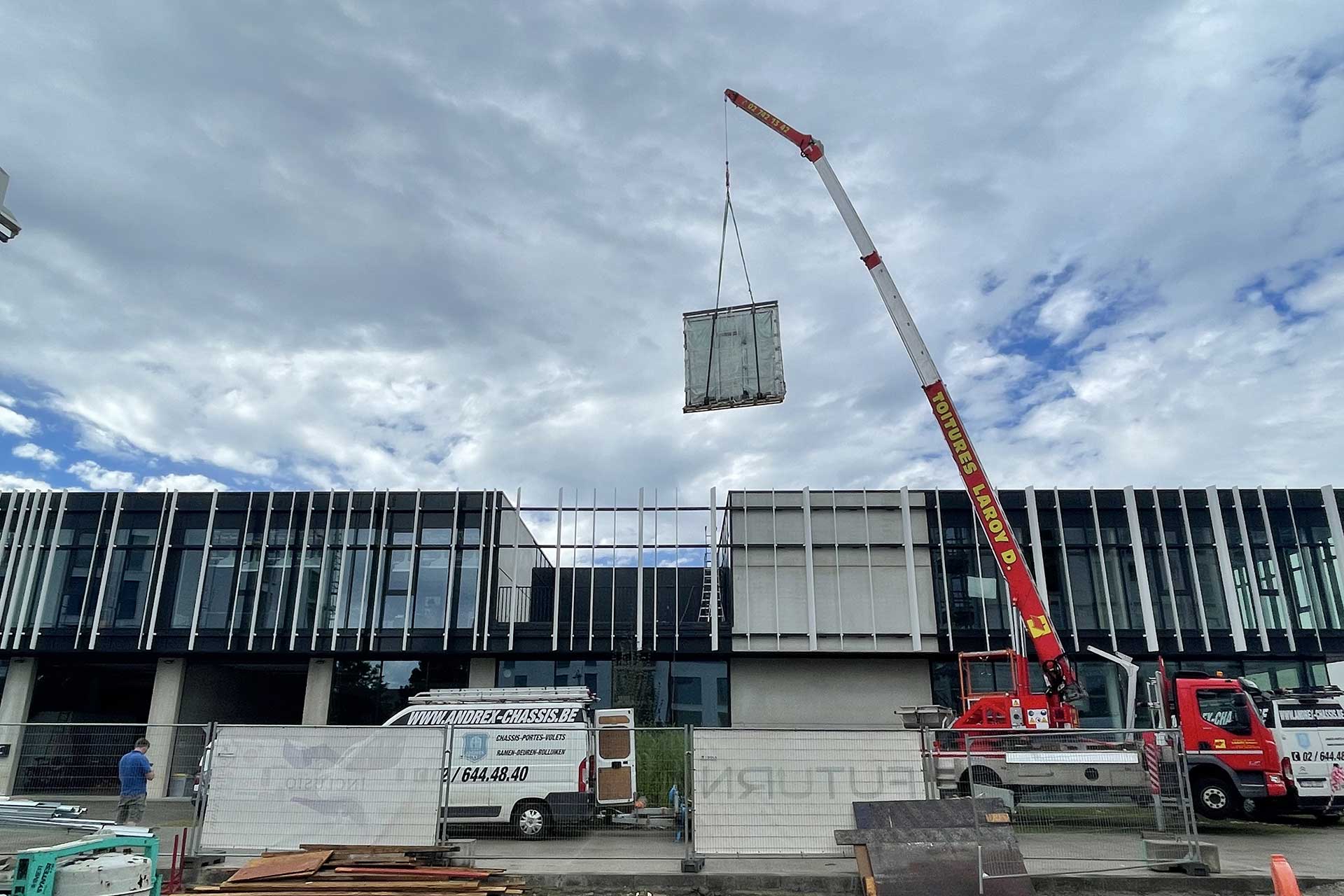 Grue levant un panneau pour la façade d'un immeuble