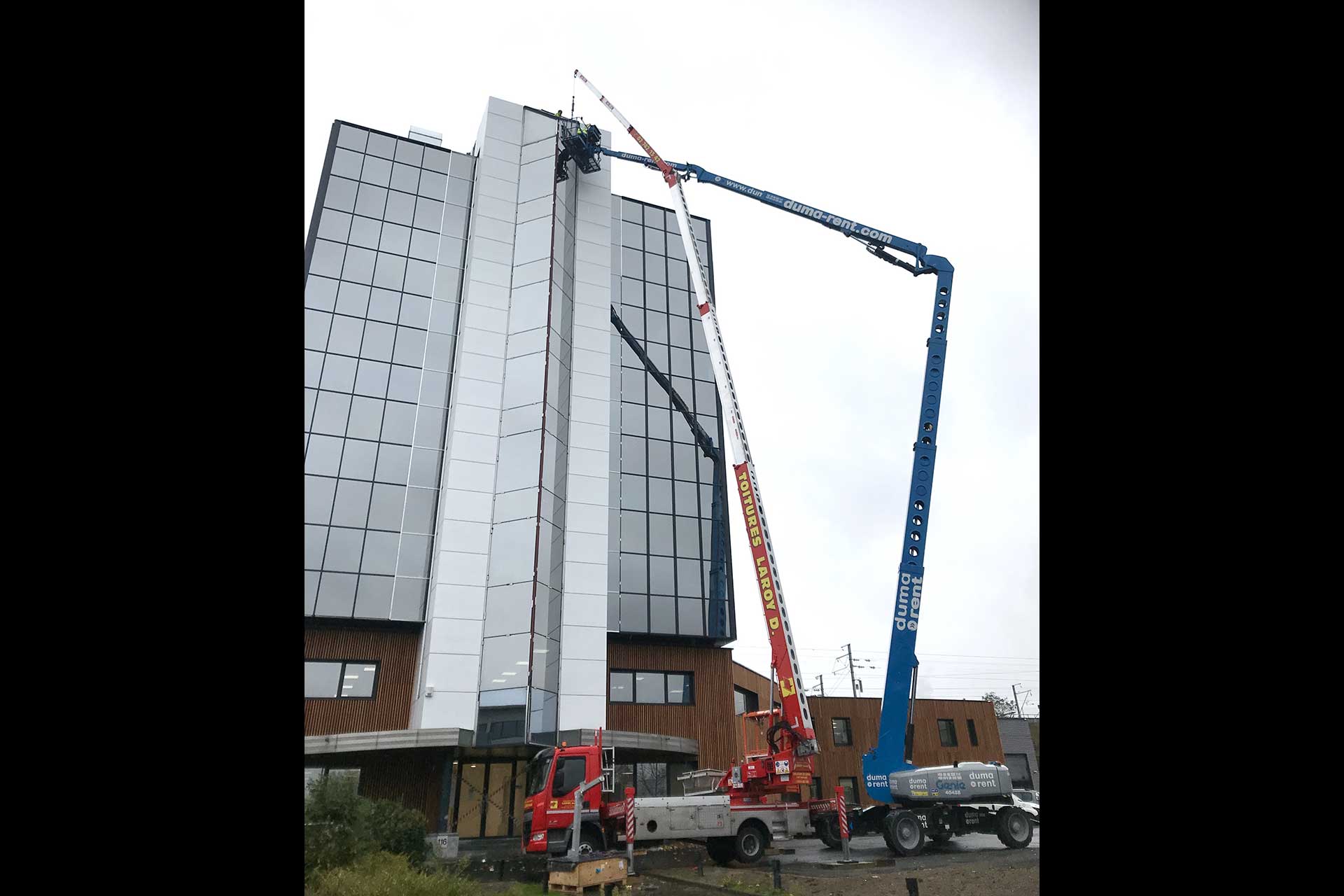 Réparation d'une vitre sur un immeuble au moyen d'une grue