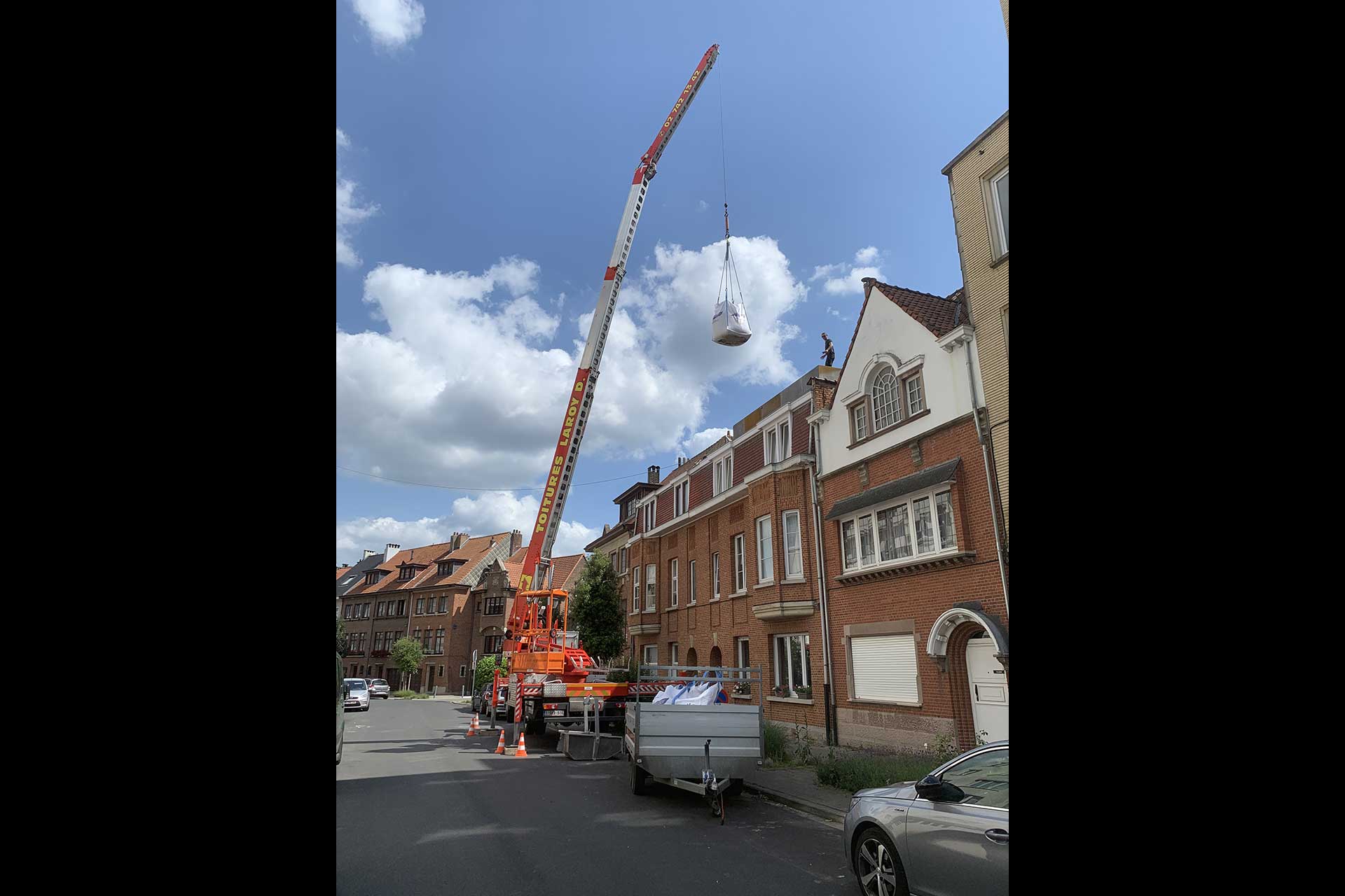 Grue levant un sac d'une tonne au dessus d'une maison