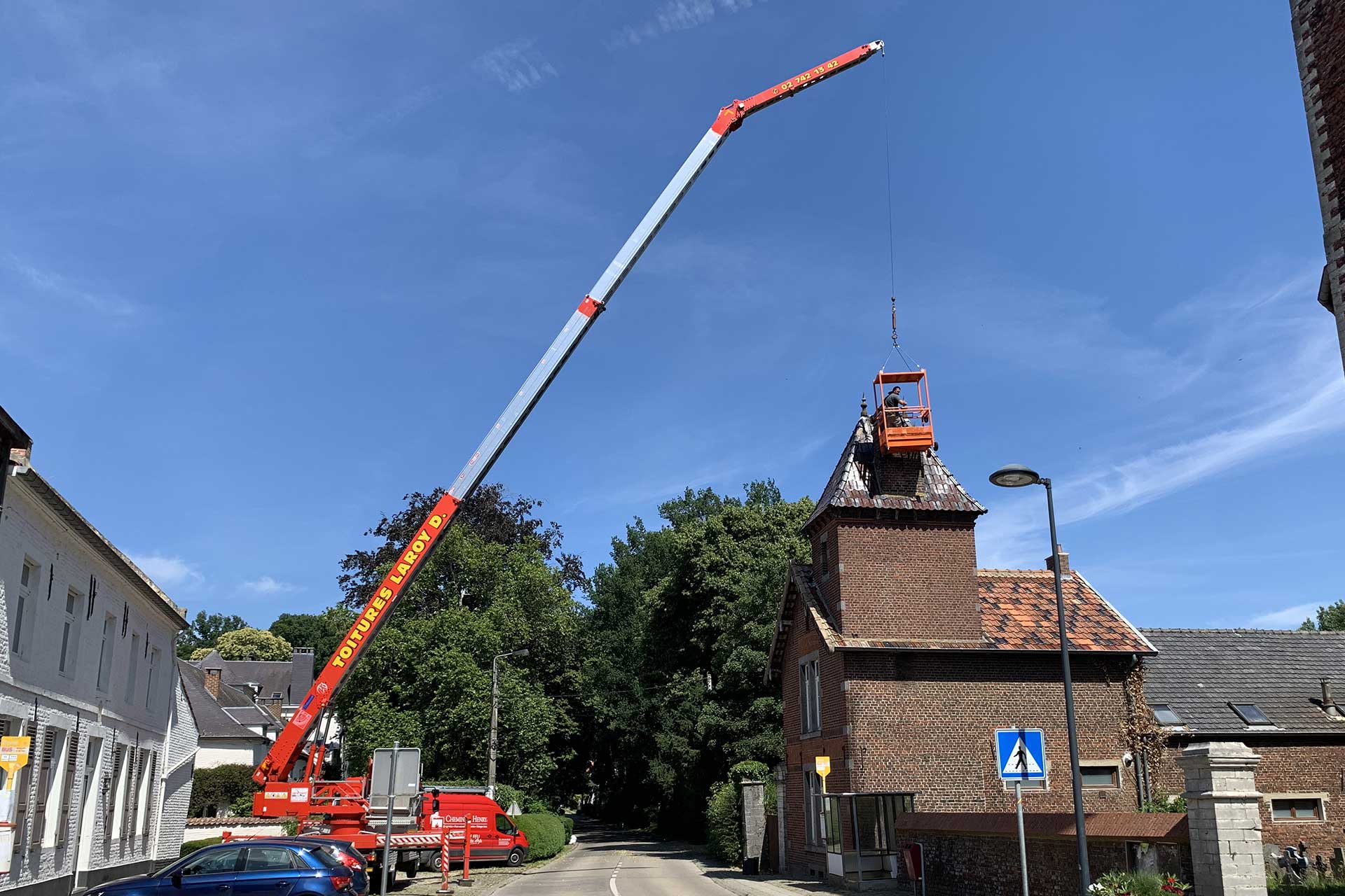 Grue avec nacelle en train de réparer un toit