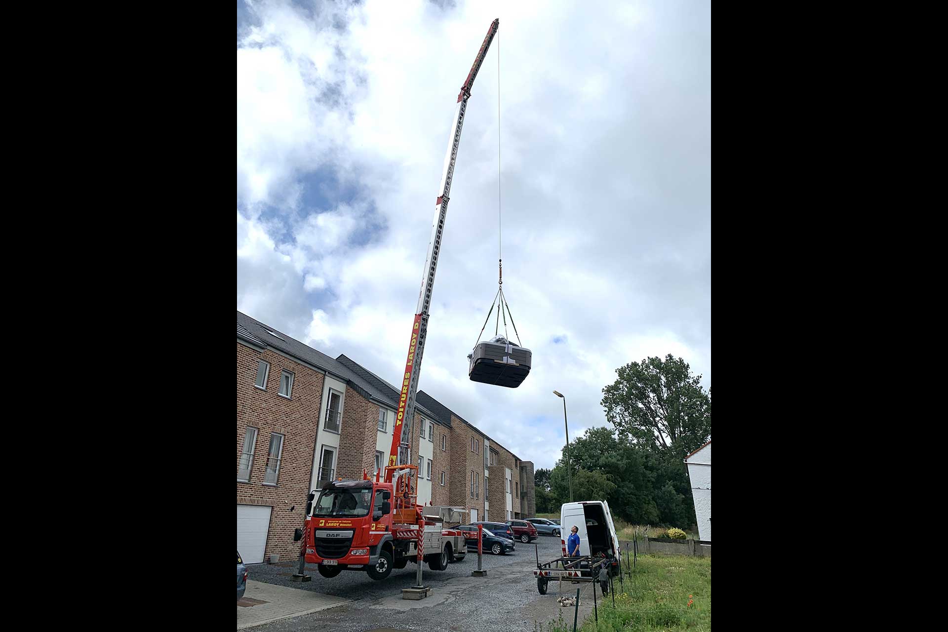 Camion grue levant un jacuzzi au dessus d'une maison